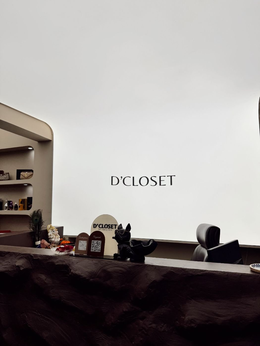 D’ Closet billing counter with textured stone front and backlit logo wall